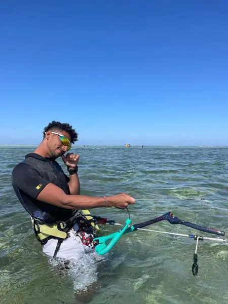 Instructor standing in shallow water holding a kite bar