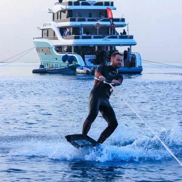 Wakeboarder in a wetsuit riding behind a yacht