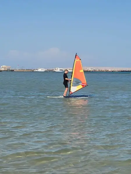 Guest windsurfing with an orange sail